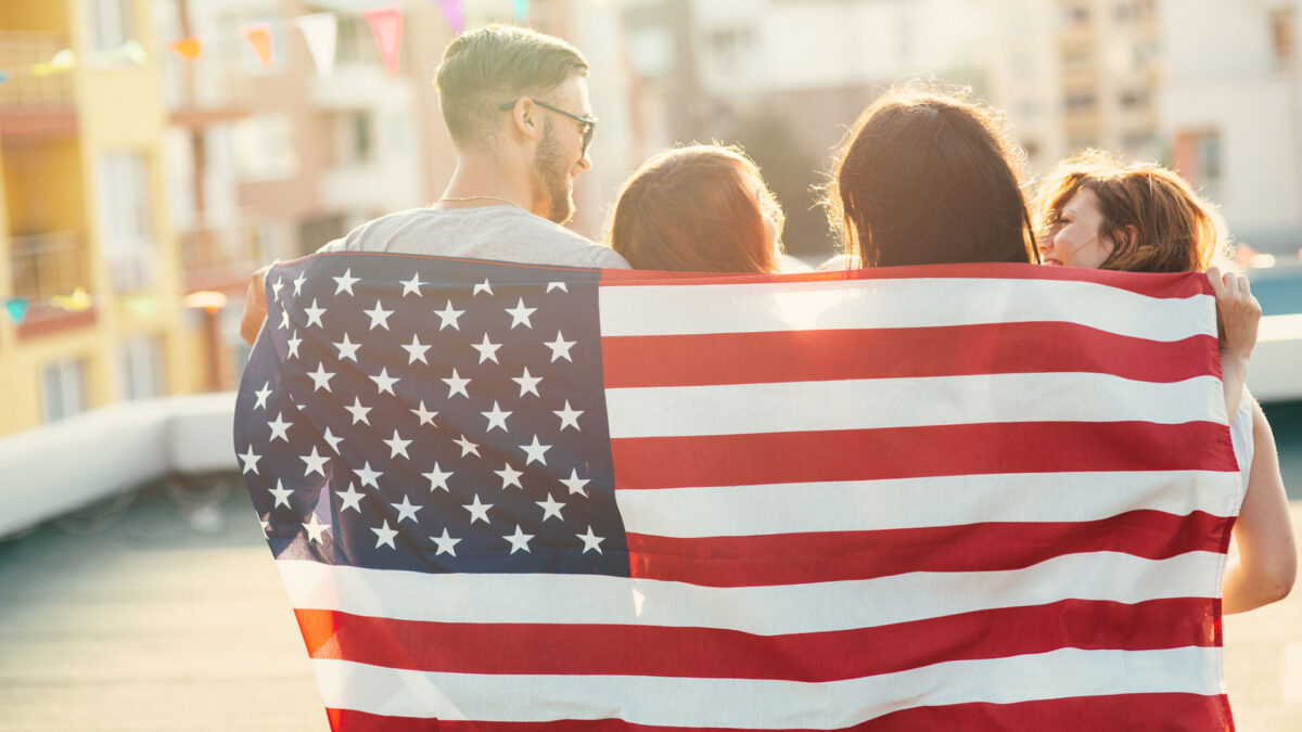 four people wrapped in an American flag