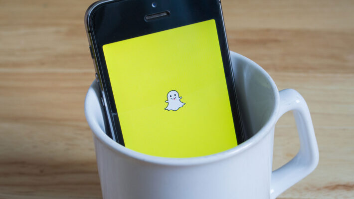 a cell phone with snapchat in a white coffee mug