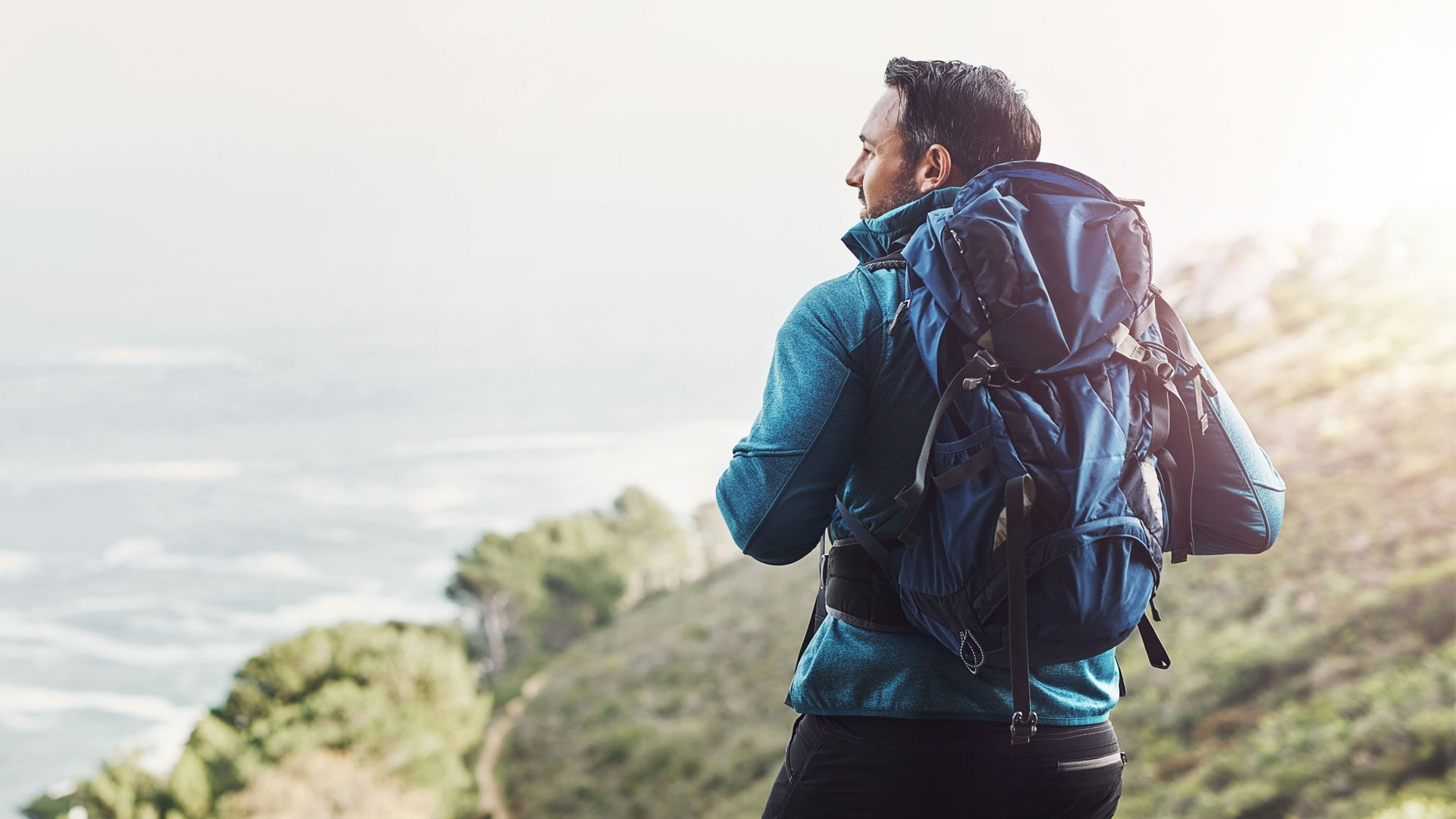 a man with a backpack on a cliff looking off into the distance