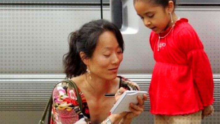 A woman taking notes while next to a young girl