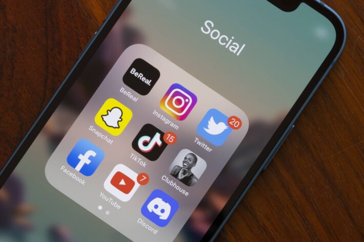 an iPhone showing a "social" folder with different mainstream social media apps