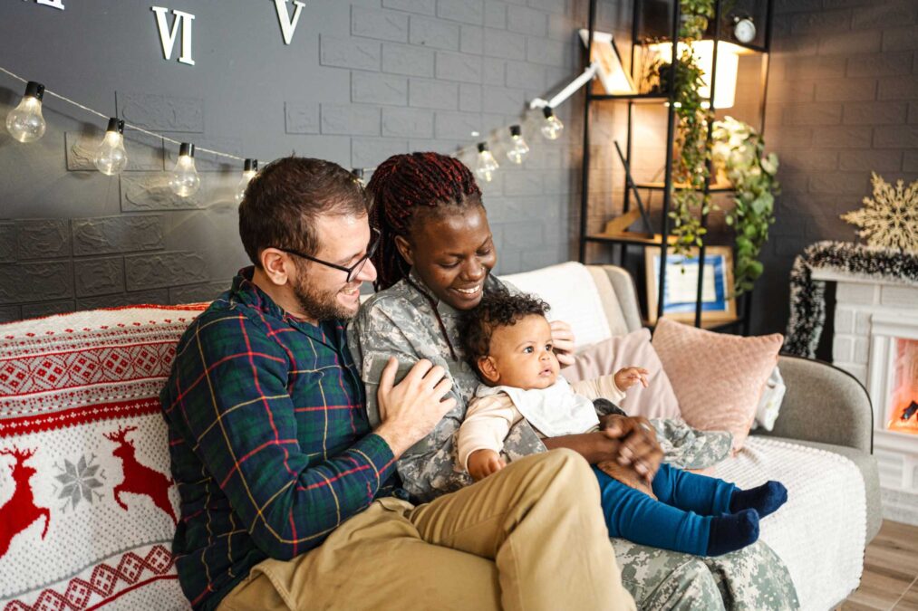 Multi-cultural family sitting together on couch in living room