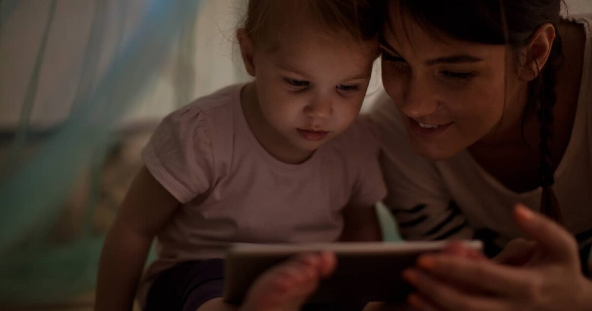 a mother with her toddler reading a book at night 