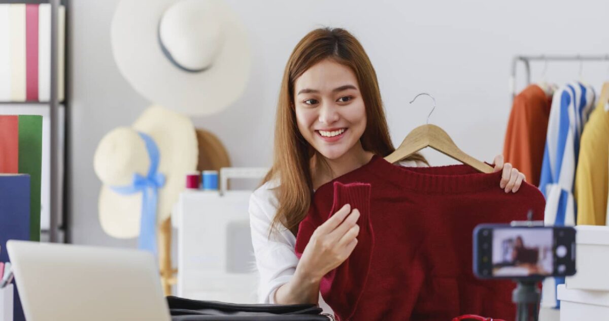 interior: a woman recording herself while holding a red sweater 