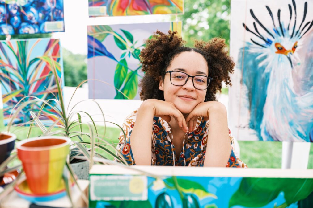 a woman sitting with her head resting on hands with colorful art surrounding her