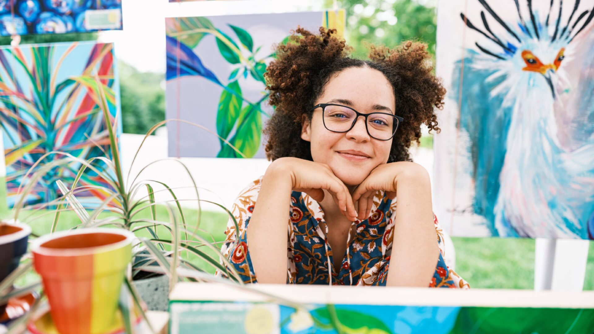 a woman sitting with her head resting on hands with colorful art surrounding her