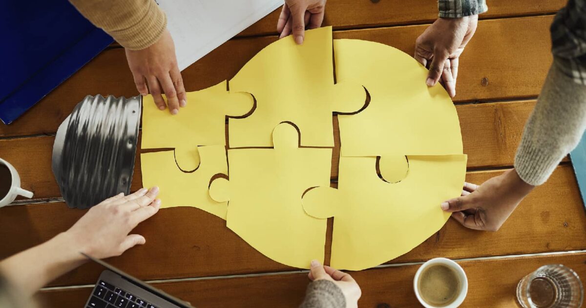 A team assembling a light bulb shape from puzzle pieces