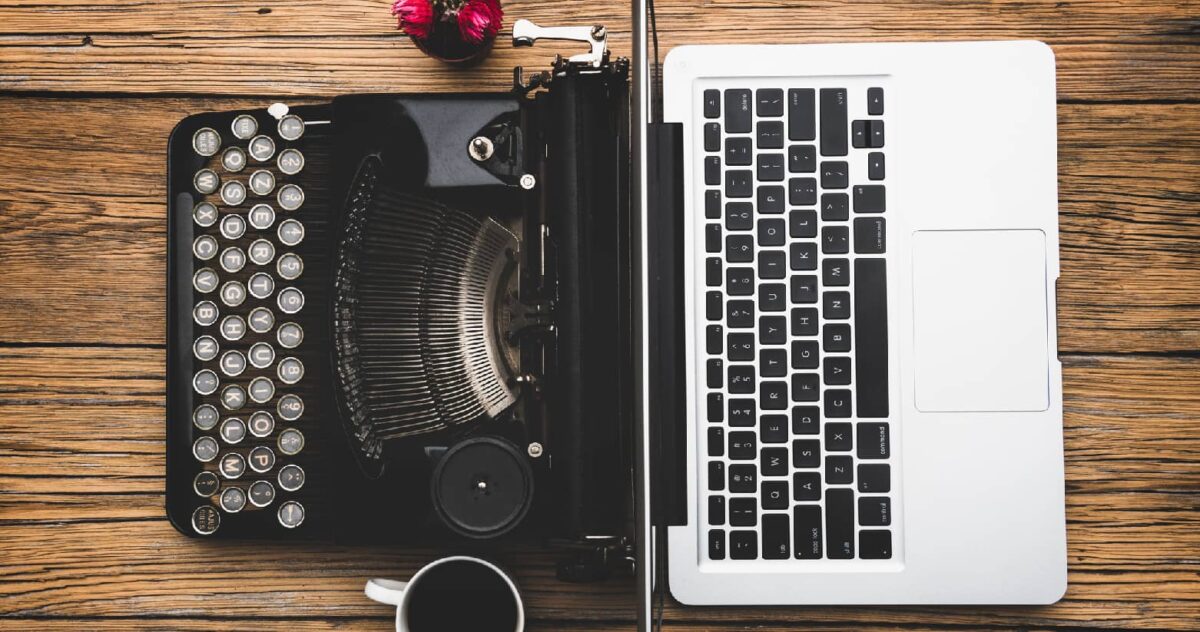 An image of a typewriter next to a modern laptop