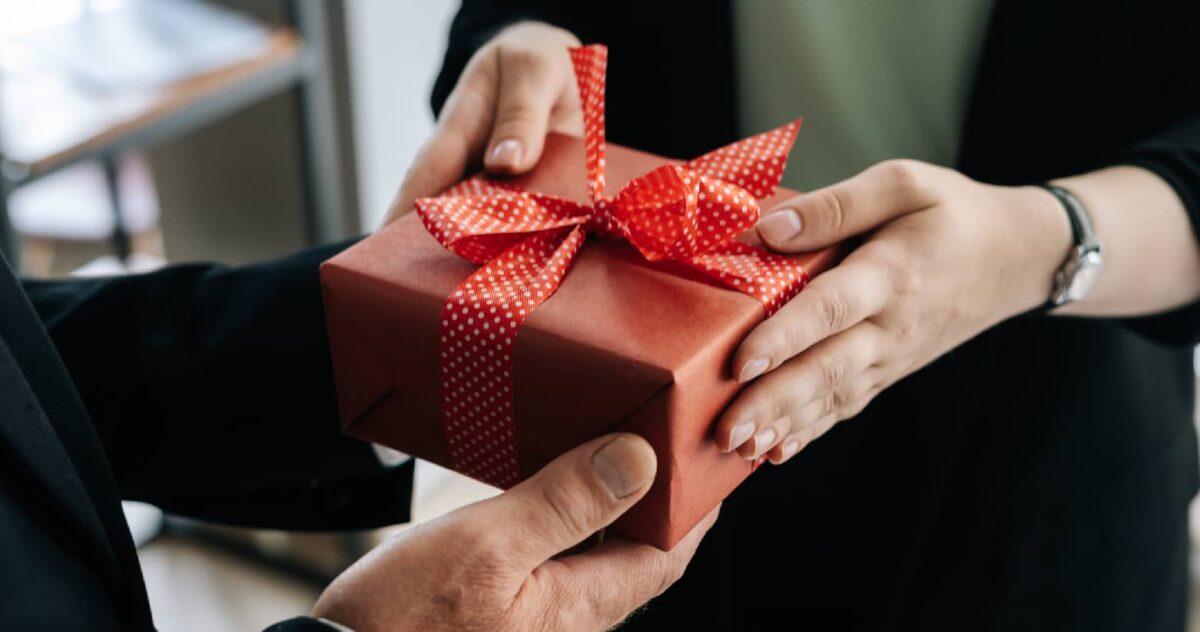 An image of one person giving a gift to another person