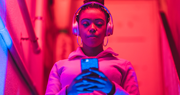 A portrait of a young black woman while she is listening to music under neon lights.
