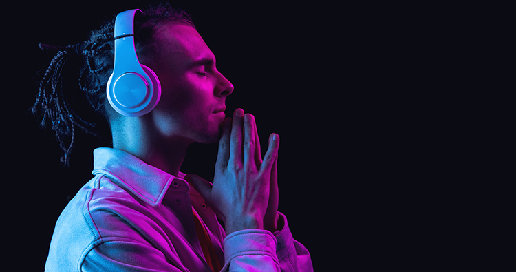 Portrait of Caucasian young man isolated on dark studio background in neon. Side view. Handsome male model in casual style. Concept of human emotions, facial expression, youth. Copy space for ad.