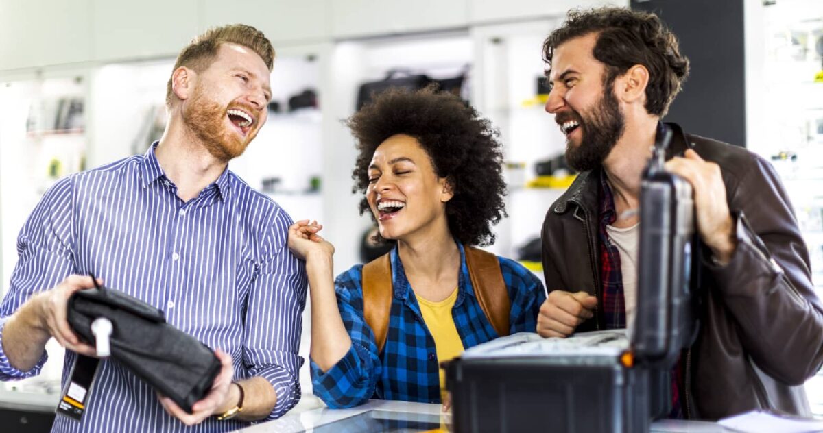 two men and a woman smiling while in a clothing store 