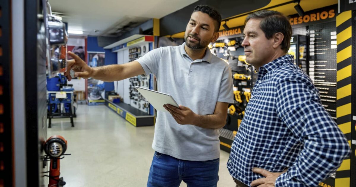 Two men in a store, one man is guiding a man on product choices 