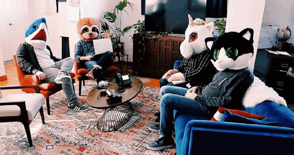 5 people wearing mascot helmets sitting in a living room