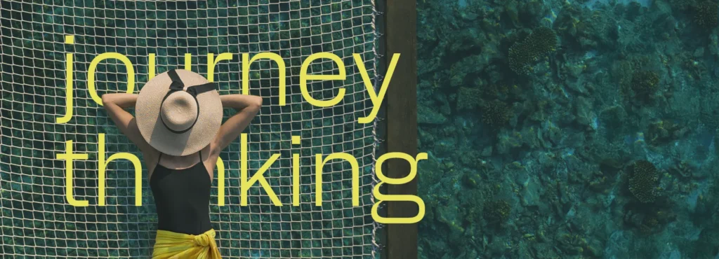 A woman relaxing on a suspended net above the sea, part of journey-based thinking in travel.